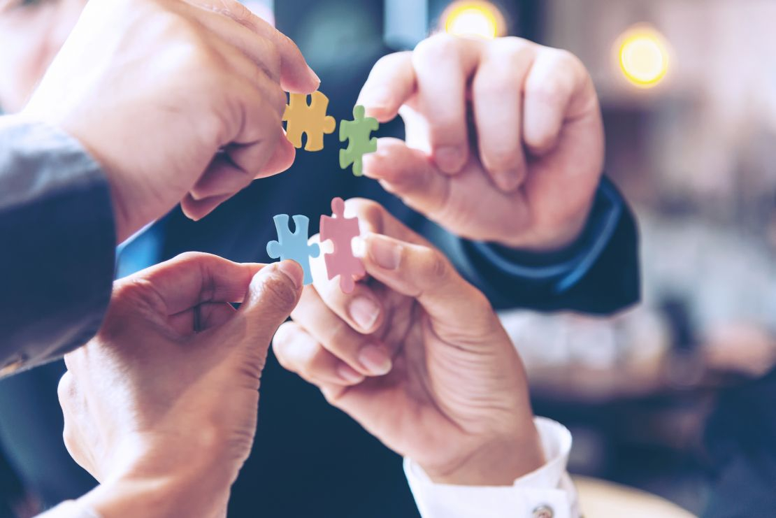 4 Hände halten 4 Puzzleteile